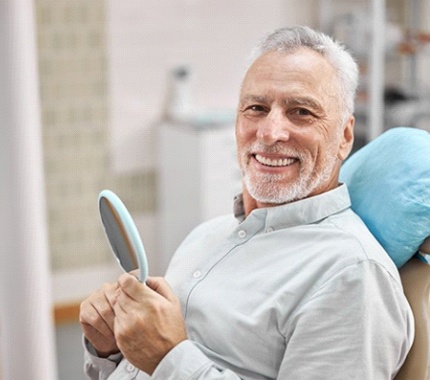 smiling dental patient holding a mirror