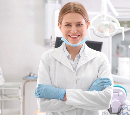A female dentist smiling with her arms folded