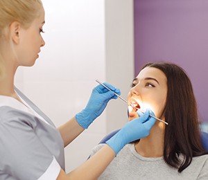 Dental team member performing oral cancer screening for young woman
