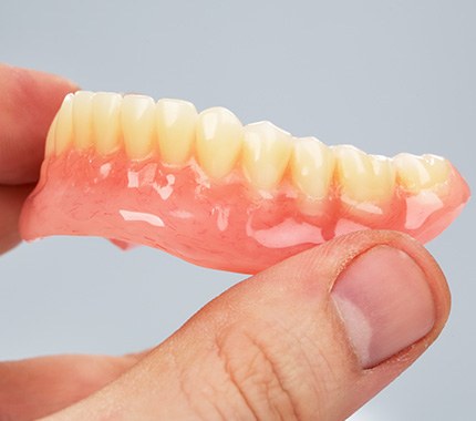 Close-up of hand holding a full denture