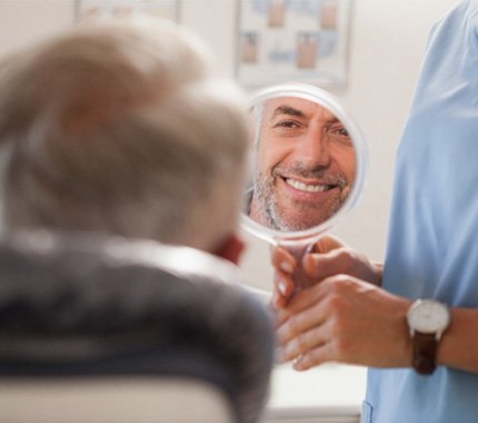 dentist holding a mirror for the smiling patient
