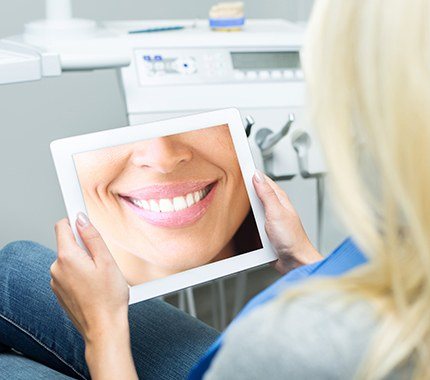 Woman looking at smile design on tablet computer