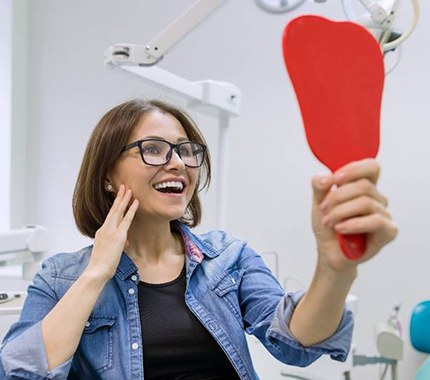young woman admiring her new dental implants in Hillsboro