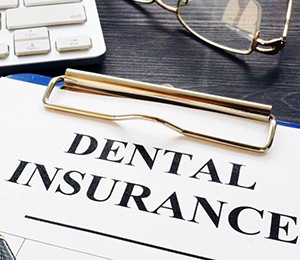A clipboard with a piece of paper that reads “Dental Insurance”