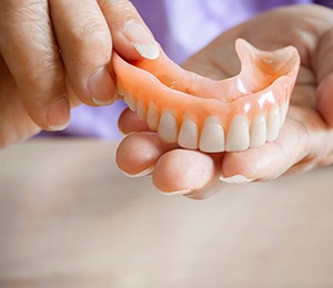 A closeup of hands holding a removable denture