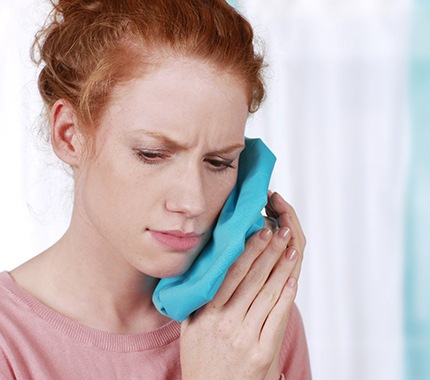 Woman holding a cold compress to her face