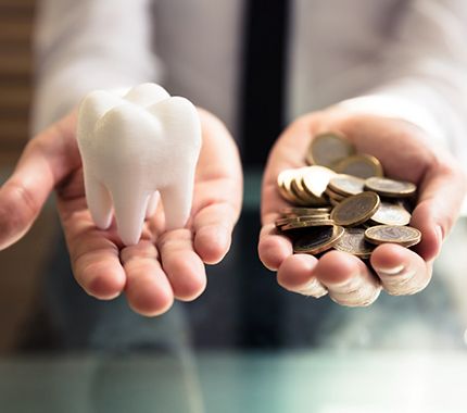 A hand holding coins and a giant model tooth