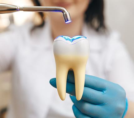 dentist using UV light on 3D model tooth 