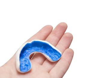 A middle-aged woman inserts a mouthguard to better protect her natural teeth and dental implants