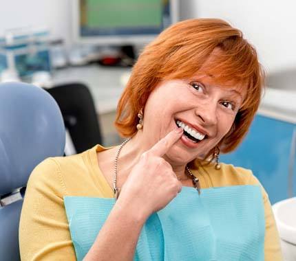 Happy woman pointing at her implant dentures in Hillsboro