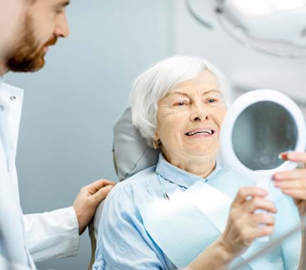 Senior woman admiring her new teeth in the mirror