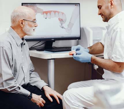 Senior man and dentist discussing candidacy for implant dentures
