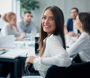 Woman smiling in meeting room with colleagues