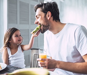 Daughter giving father a bite of her sandwich