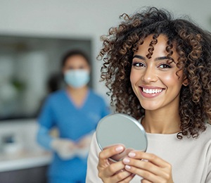 Woman smiling while holding small mirror
