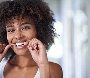 Woman smiling while flossing teeth