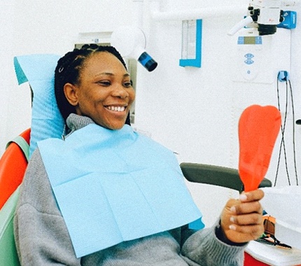 Woman in dental chair looking at smile in mirror