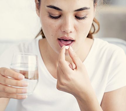 Woman taking a pill for oral conscious sedation in Hillsboro.