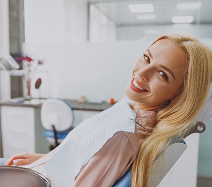 Blonde woman sitting in a dental chair and smiling