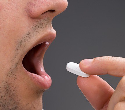 close up of dental patient taking oral sedative pill