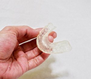 TMJ splint in patient’s hand on white background