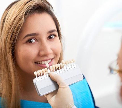 cosmetic dentist in Hillsboro holding a row of veneers in front of a patient’s smile 