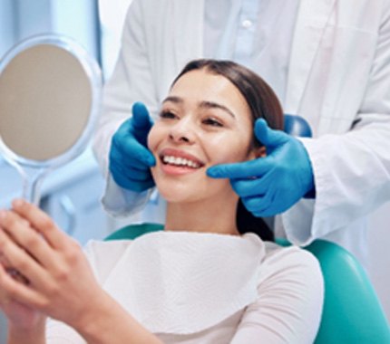  Woman with white teeth smiling at reflection in mirror