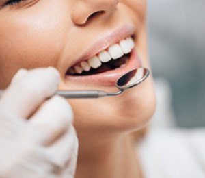Dentist using dental mirror to look at patient's teeth