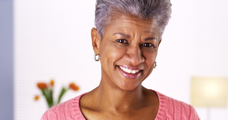 older woman smiling happily after receiving dental implants