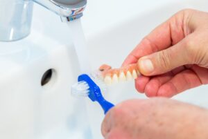 Upper denture being cleaned in a sink